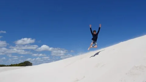 Fun jumping challenge into soft white dune sand Stock Footage 106938884