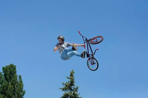 Fun jumping. Young boy, the cycler, soaring high in the blue sky with  bike Stock Photos