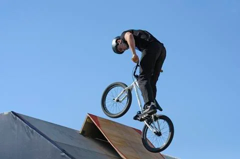 Fun jumping. Young boy, the cycler, soaring high in the blue sky with the bike Stock Photos