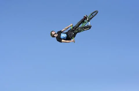 Fun jumping. Young boy, the cycler, soaring high in the blue sky with the bike Stock Photos