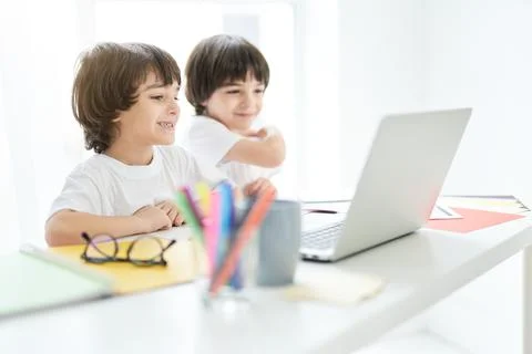 Fun learning. Cute latin boy looking cheerful, sitting with his brother at the Stock Photos
