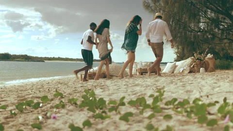Fun millennial friends run and sit on sandy beach chairs under sunny blue sky in Stock Footage 199461817