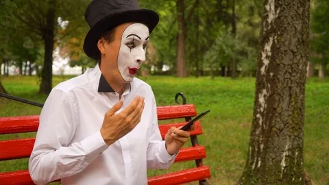 Fun mime sits on a park bench with a phone Stock Footage 116174865