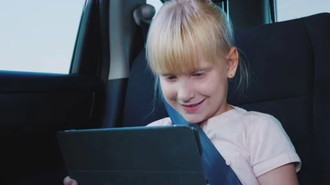 Fun on the road. The girl uses a tablet, rides in the back seat of the car Stock Footage 79005875