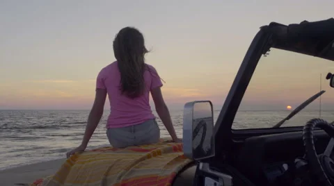 Fun Teen Sits On Hood Of Jeep, Watches Sunset On The Beach, Holds Up Peace Signs Stock Footage