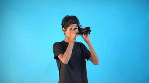 Fun young Indian boy in basic black t-shirt isolated on blue background Stock Footage 163826258