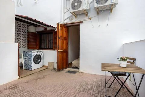 Functional patio with laundry corner, seating area and open wooden door Foto stock