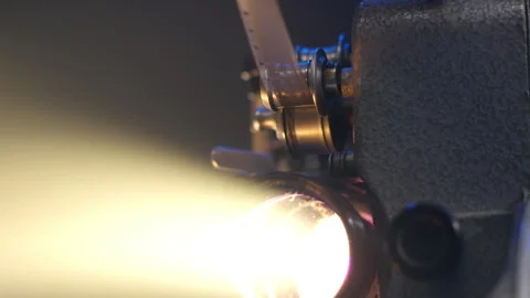 Functioning antique retro film projector casts a warm light beam onto a rotating Stock Footage 272744973