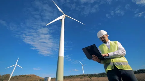 Functioning wind turbine towers and an energetics worker standing beside them Video stock 97989550