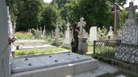 Funeral gothic girl walking beside tombstones in ancient graveyard contemplat Stock Footage