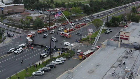 A funeral procession lead by a white hearse drives past a community Stock Footage 172550577