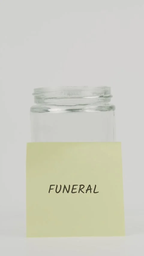 Funeral text or word on yellow sticky note attached to glass jar with hand Stock Footage 311736903