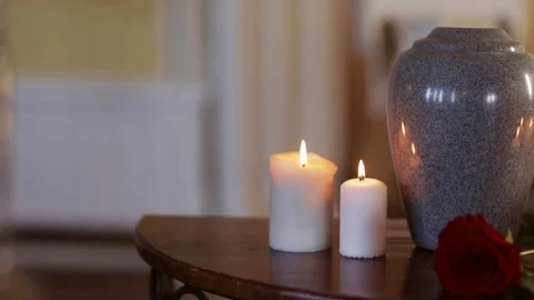 Funerary urn and candles on table burning indoors Stock Footage 74133345