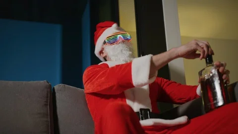 Funky bad Santa Claus drinking from a whiskey bottle and enjoying some music whi Stock Footage 120585896