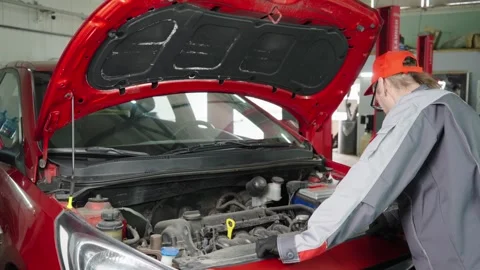 A funny 50 years old auto mechanic tries to fix a car Video stock 332765658