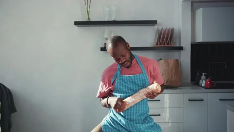 Funny amusing african american man in apron dancing and having fun with loaf of Stock Footage 131668763