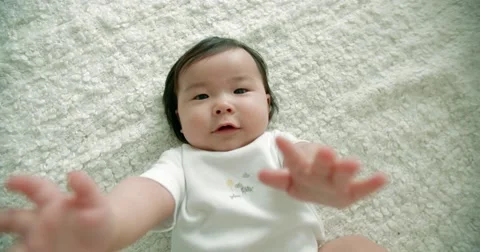 Funny Asian baby pulls his hands to the top Stock Footage