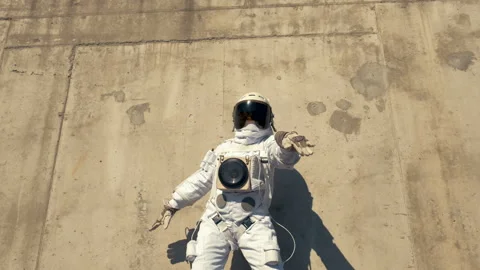 Funny astronaut makes dancing. Against a background of a concrete wall. Stock Footage 88834891