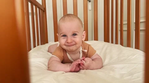 Funny baby boy lying in bed looking at camera. Adorable six months old child Stock Footage 245667618