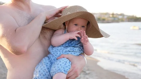 Funny Baby wearing a big straw hat. a man holds his small baby girl infant on Stock Footage 99151253