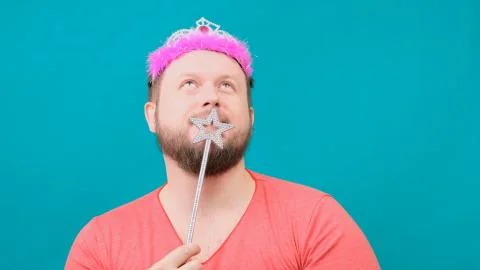 Funny bearded freaky man in a pink T-shirt with a deadema on his head is Stock Photos