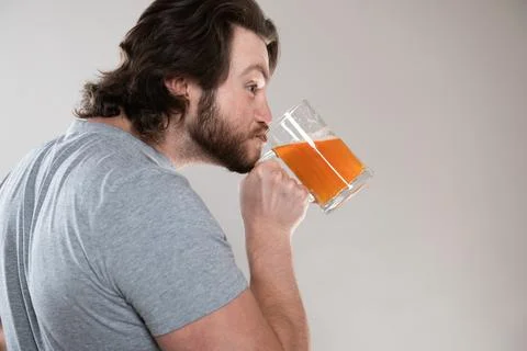 Funny bearded man drinking beer with a big mug on a gray background Stock Photos