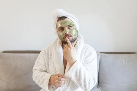 Funny bearded man is having fun with a cosmetic mask on his face made of green Stock Photos