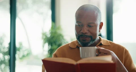 Funny, black man and reading book in home with tea, relax and literature on Stock Footage 337756762