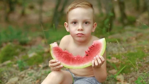 Funny boy appetizingly eating a huge piece of ripe and juicy watermelon Stock Footage 87750706