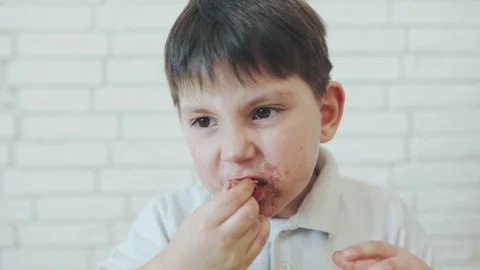 Funny boy. A Caucasian boy is sitting at a table and eating ice cream. Child Stock Footage 128430053