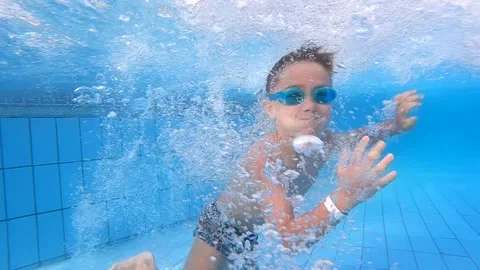 Funny boy dives under the water into the pool, enjoys swimming in crystal clear Stock Footage 246113279
