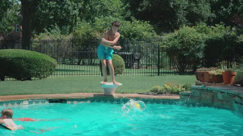 Funny boy does silly dance on diving board during summer pool party Stock Footage 248078672