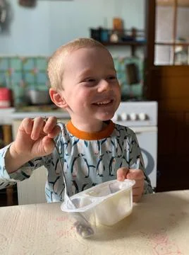 Funny boy eats yogurt in the kitchen Stock Photos