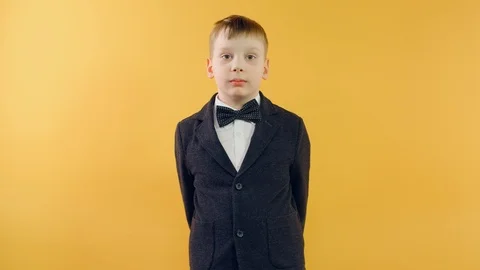 Funny boy fixing bow tie looking at camera and smiling on yellow background Video stock 126331824