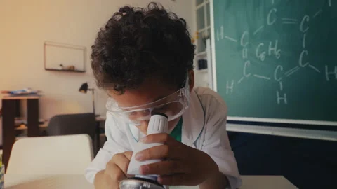 Funny boy in lab coat examines sample under microscope, shocked by result Video stock 274837039