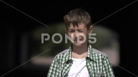 Funny boy look into the camera and squint from the sun Stock Photos