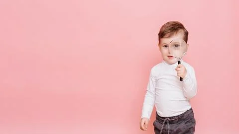Funny boy looking through magnifying glass with surprise Stock Photos