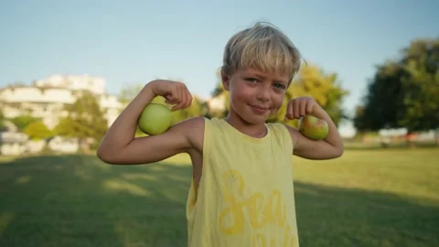 Funny boy with red apples shows biceps. Video stock 208696710
