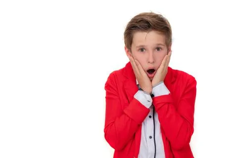 A funny boy in a red jacket is surprised. He put his hands to his cheek and.. Stock Photos