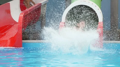 Funny boy sliding in a round pipe and cheery girl riding in semi-tube in slo-mo Stock Footage 112923747