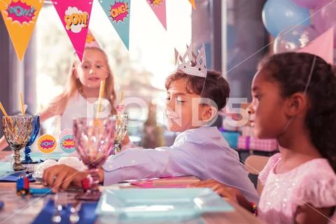 Funny boy smiling and taking party horn from the table Stock Photos
