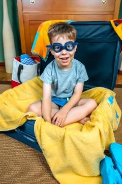 Funny boy smiling sitting inside a suitcase Stock Photos