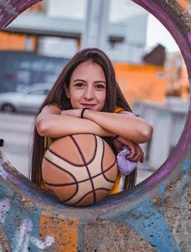 A funny brunette girl poses with the ball while leaning on a hole. Stock Photos