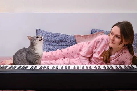 Funny cat singer amusingly sings along to a woman playing an electric piano o Stock Photos