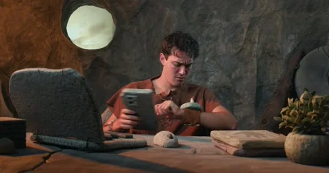 Funny Caveman Checking Stone Smartwatch and Working on Laptop in Prehistori.. Stock Footage 337217426