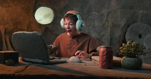 Funny Caveman on Video Call Wearing Headphones and Talking into Prehistoric.. Stock Footage 337217451