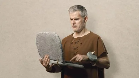 Funny Caveman Working on a Primitive Stone Laptop - Prehistoric Stock Photos