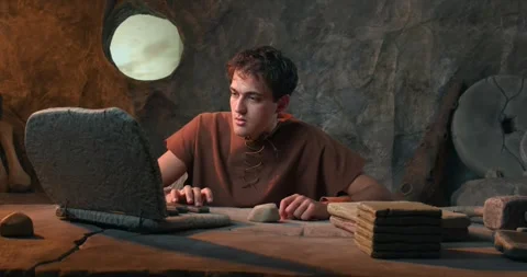 Funny Caveman Working on Stone Laptop and Hitting it with Hammer in Prehist.. Stock Footage 337217368