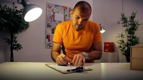 Funny character working late at the office under a desk lamp, puts away his work Vídeo Stock 32723792