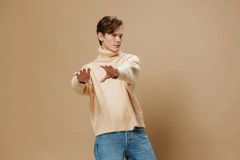 Funny, cheerful guy in a long oversized beige sweater poses amusingly Stock Photos